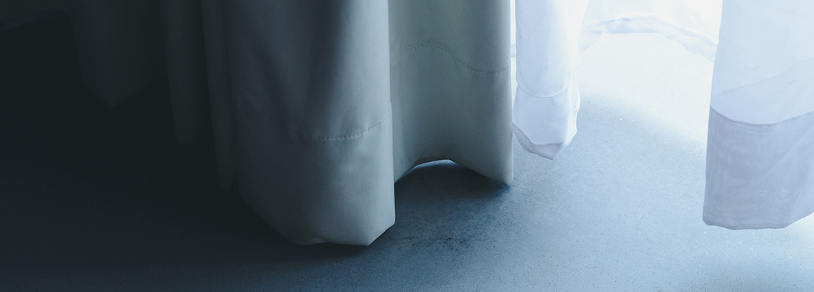 Die Vorhänge sind teilweise zugezogen, durch sie fällt sanftes Licht, das Schatten auf einen glatten, hellen Boden wirft.