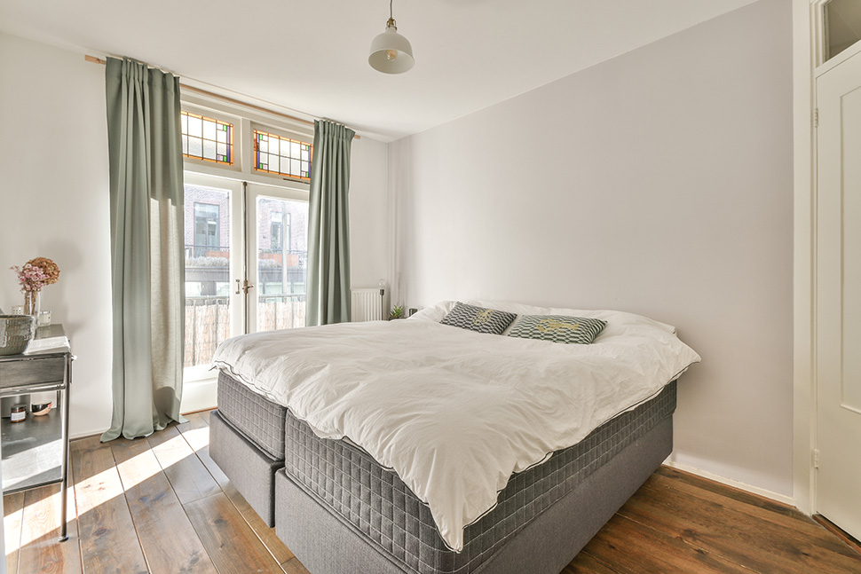 Helles Schlafzimmer mit grau-grünen Vorhängen